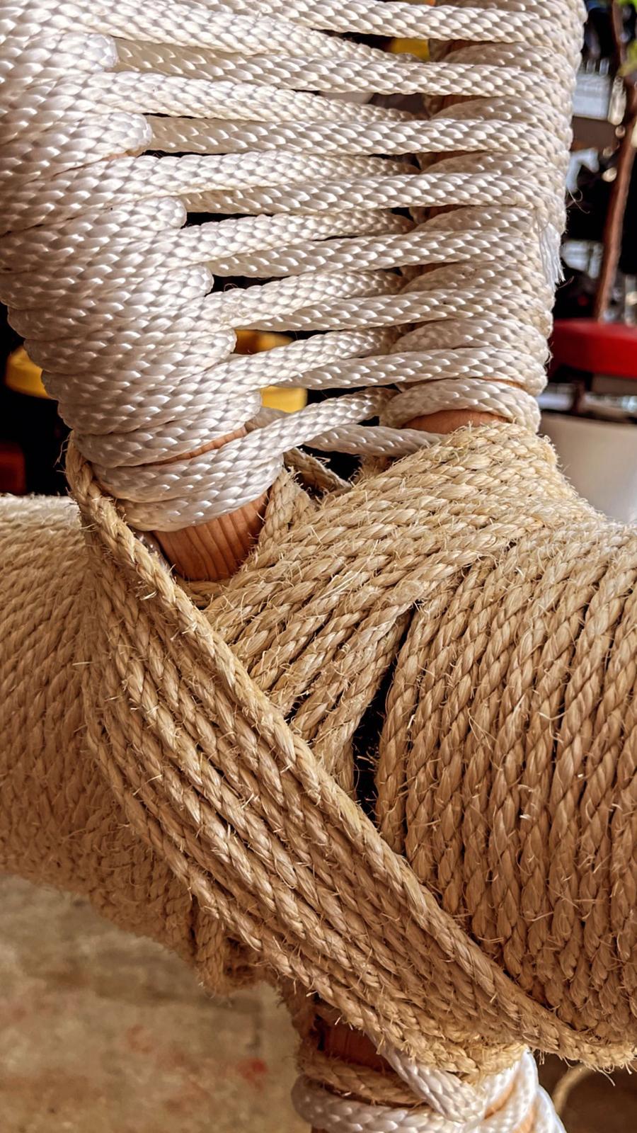 Close-up of white woven rope crossing over the natural jute wrap on the cat tree.